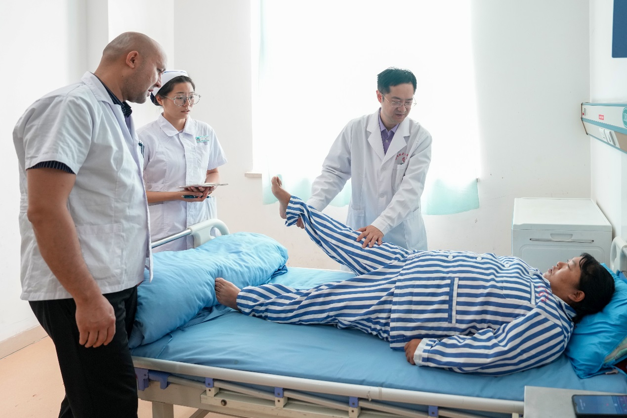 在和田地區(qū)人民醫(yī)院掛職骨科副主任的北京積水潭醫(yī)院脊柱外科副主任醫(yī)師于杰（右一），在進(jìn)行教學(xué)查房，講解腰椎間盤突出癥患者體格檢查要點(diǎn)，并為該患者即將進(jìn)行的腰椎微創(chuàng)手術(shù)進(jìn)行方案設(shè)計(jì)和術(shù)前準(zhǔn)備。