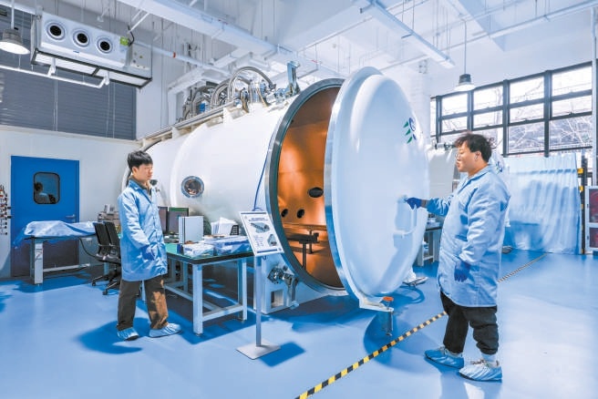 在金隅智造工場商業(yè)航天企業(yè)易動宇航生產(chǎn)車間，研發(fā)人員在真空模擬艙前進(jìn)行點火測試。
